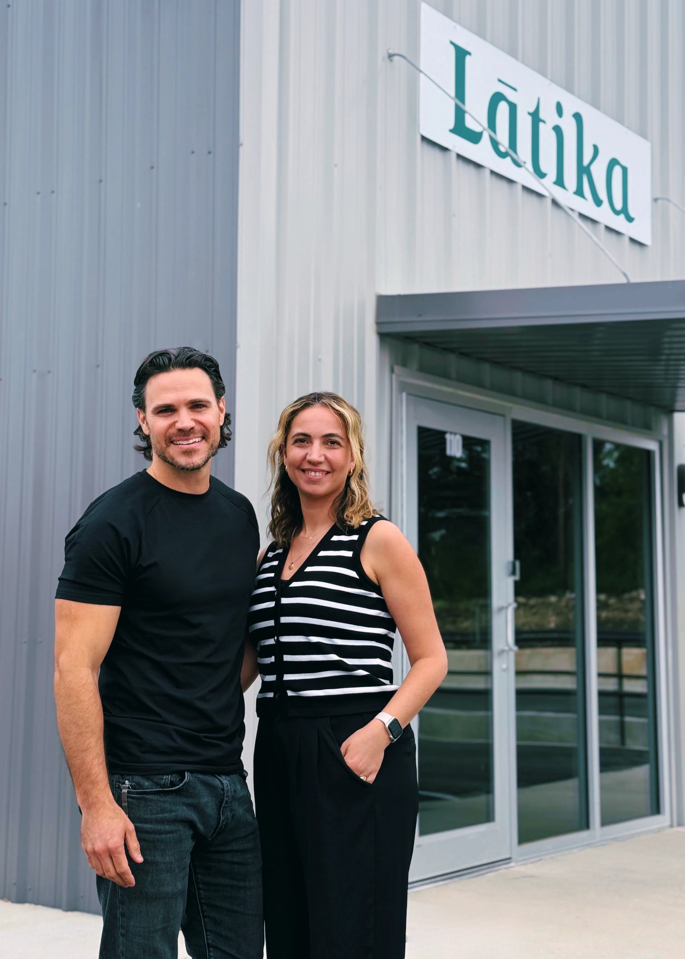 Two people standing in front of a building with 'Lätika' signage.