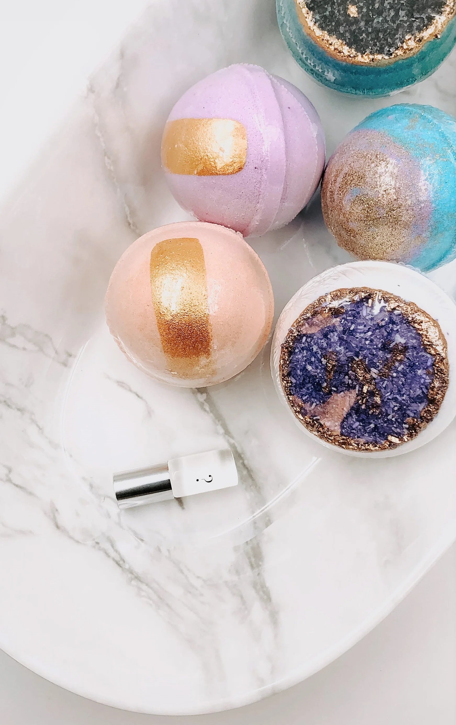 Colorful bath bombs with gold and purple accents on a marble surface