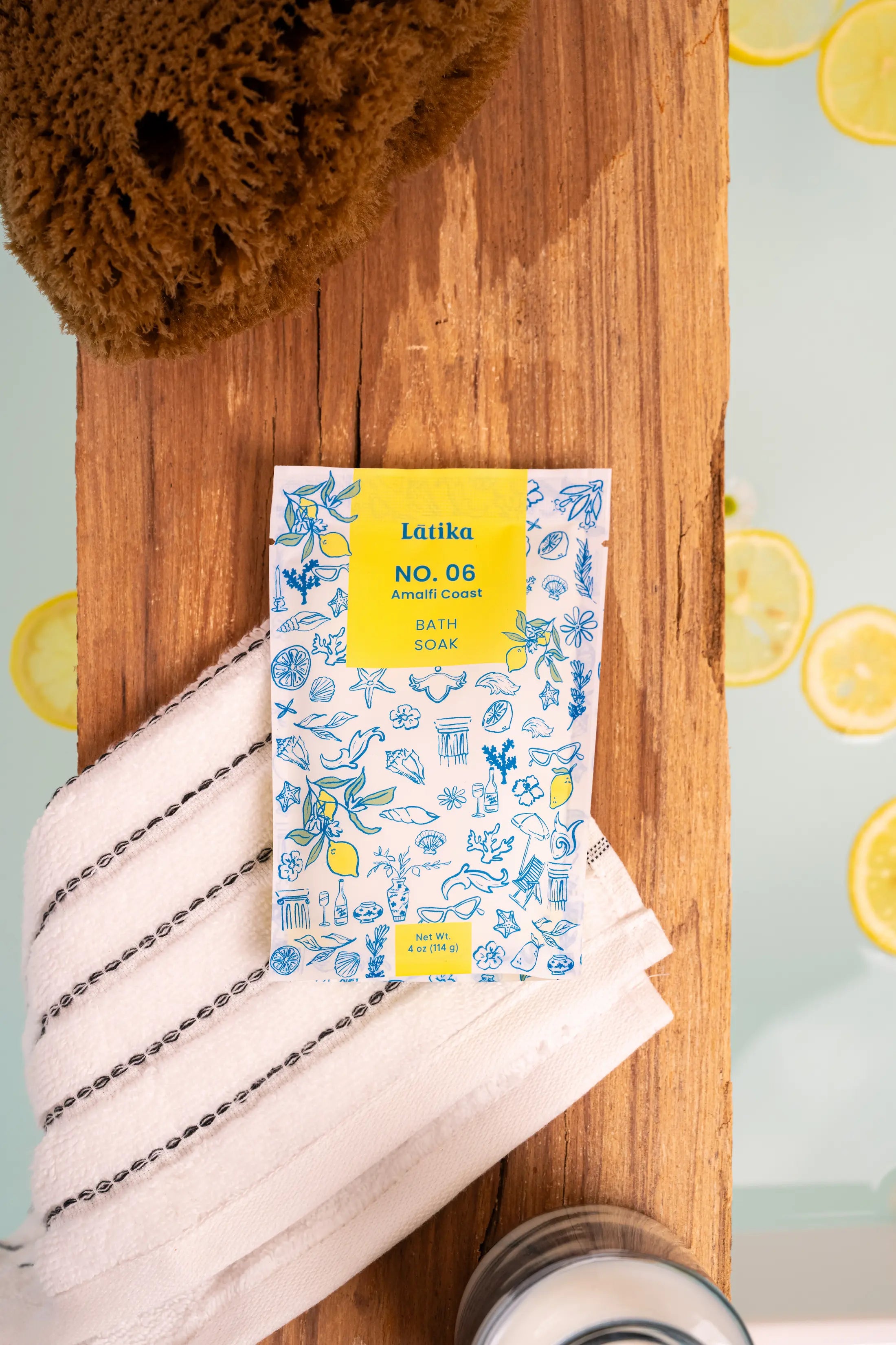Latika No. 06 bath salt packaging on a wooden board with lemons and a sponge.