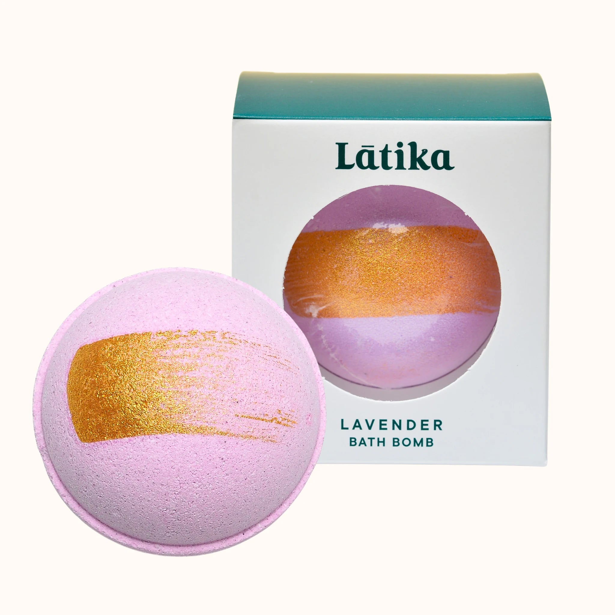 Lavender bath bomb with gold stripe next to its packaging for a relaxing soak