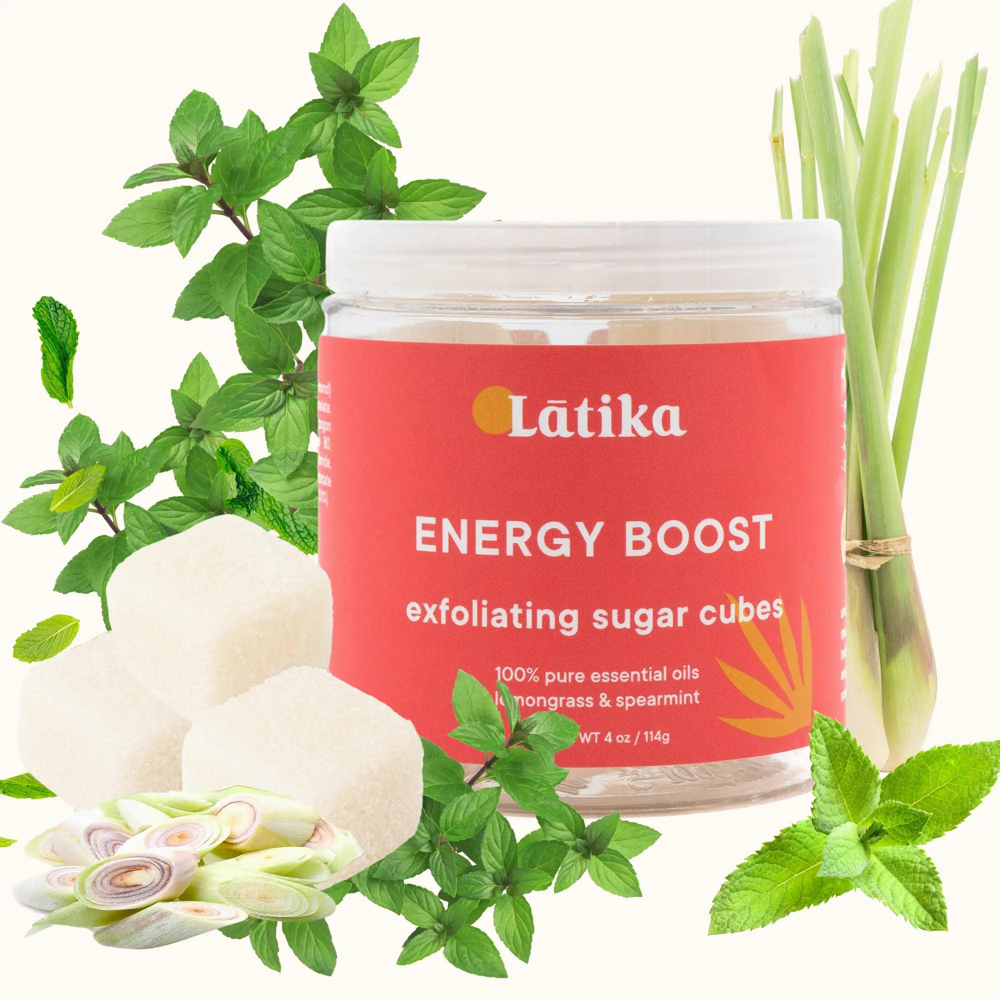 Jar of Latika Energy Boost exfoliating sugar cubes with greenery on a white background