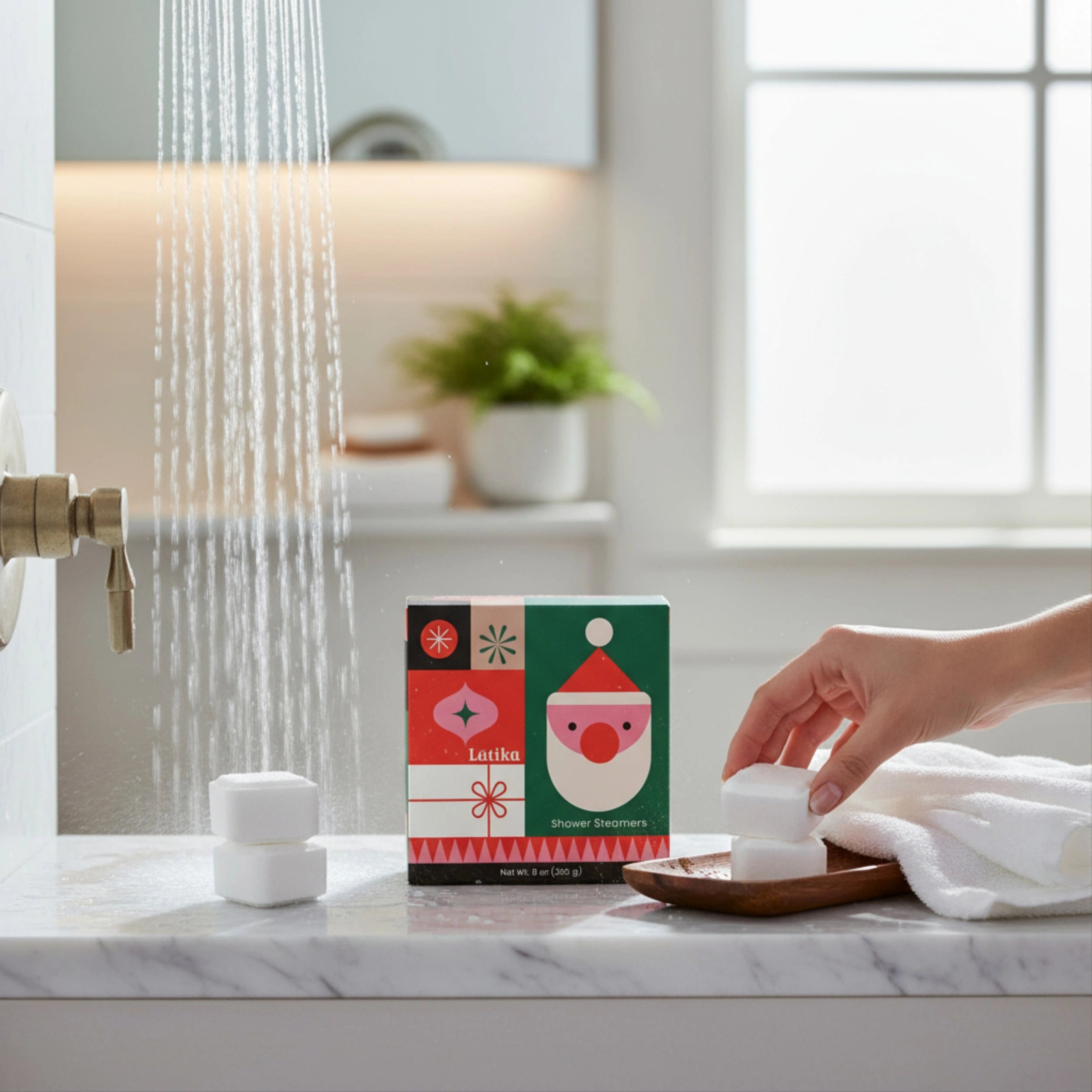 Hand holding a shower steamer tablet next to a box on a bathroom counter with running water.