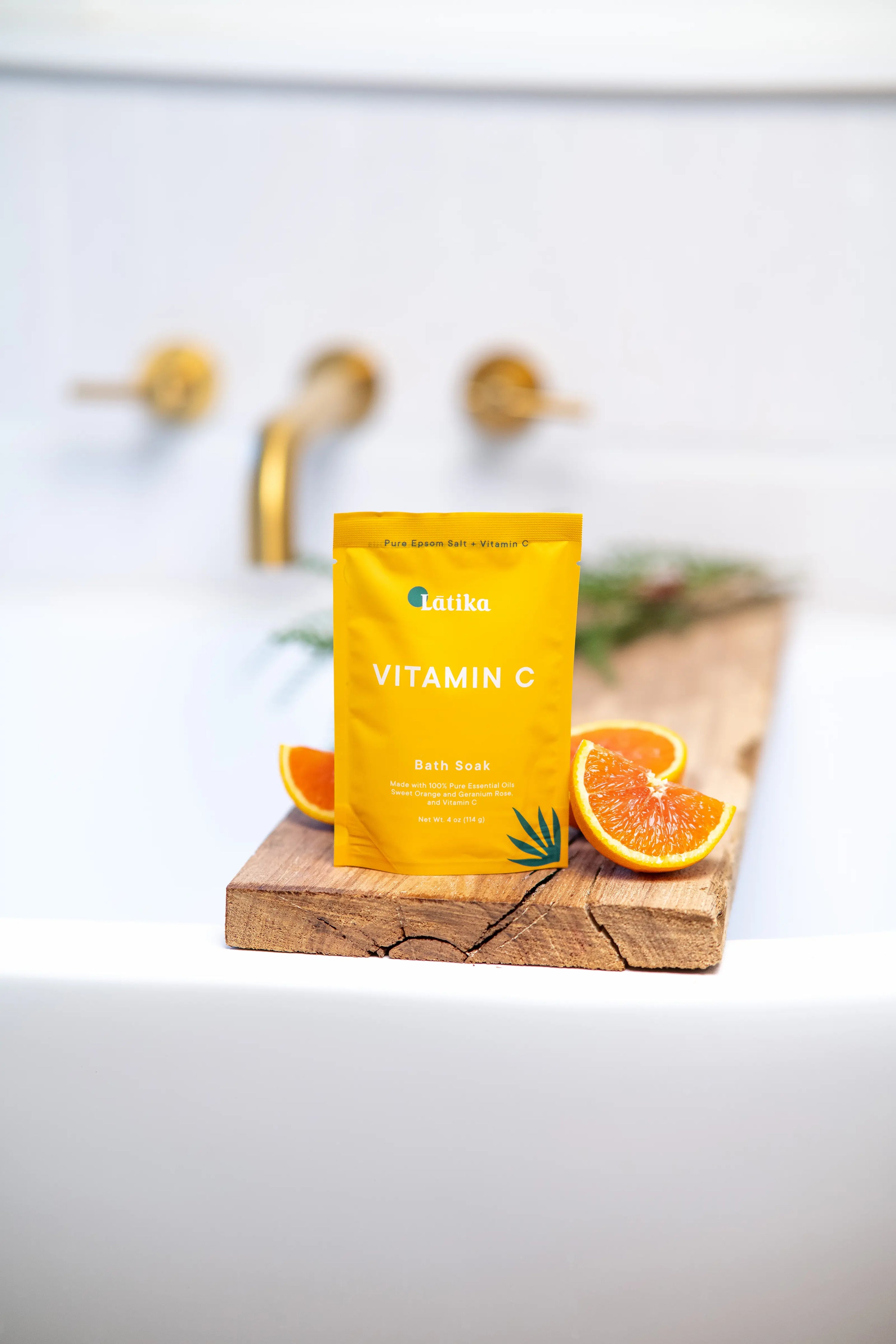 Yellow vitamin C bath salt package on a wooden cutting board with oranges in the background.
