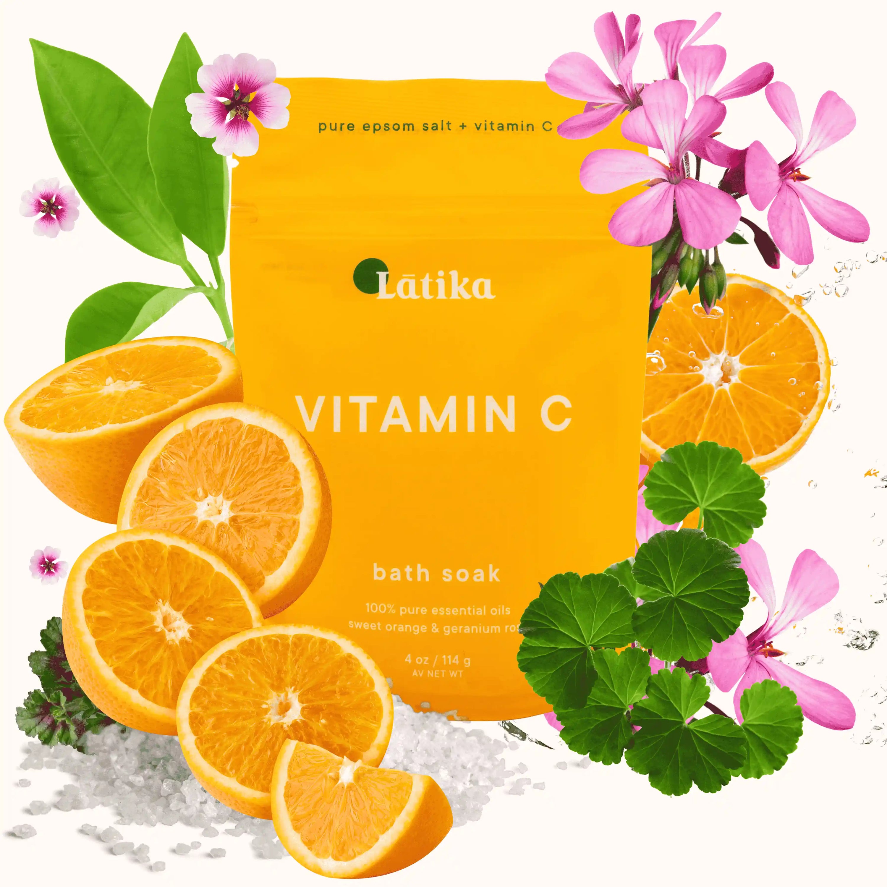 Orange packaging of a vitamin C bath soak with oranges, flowers, and green leaves on a white background