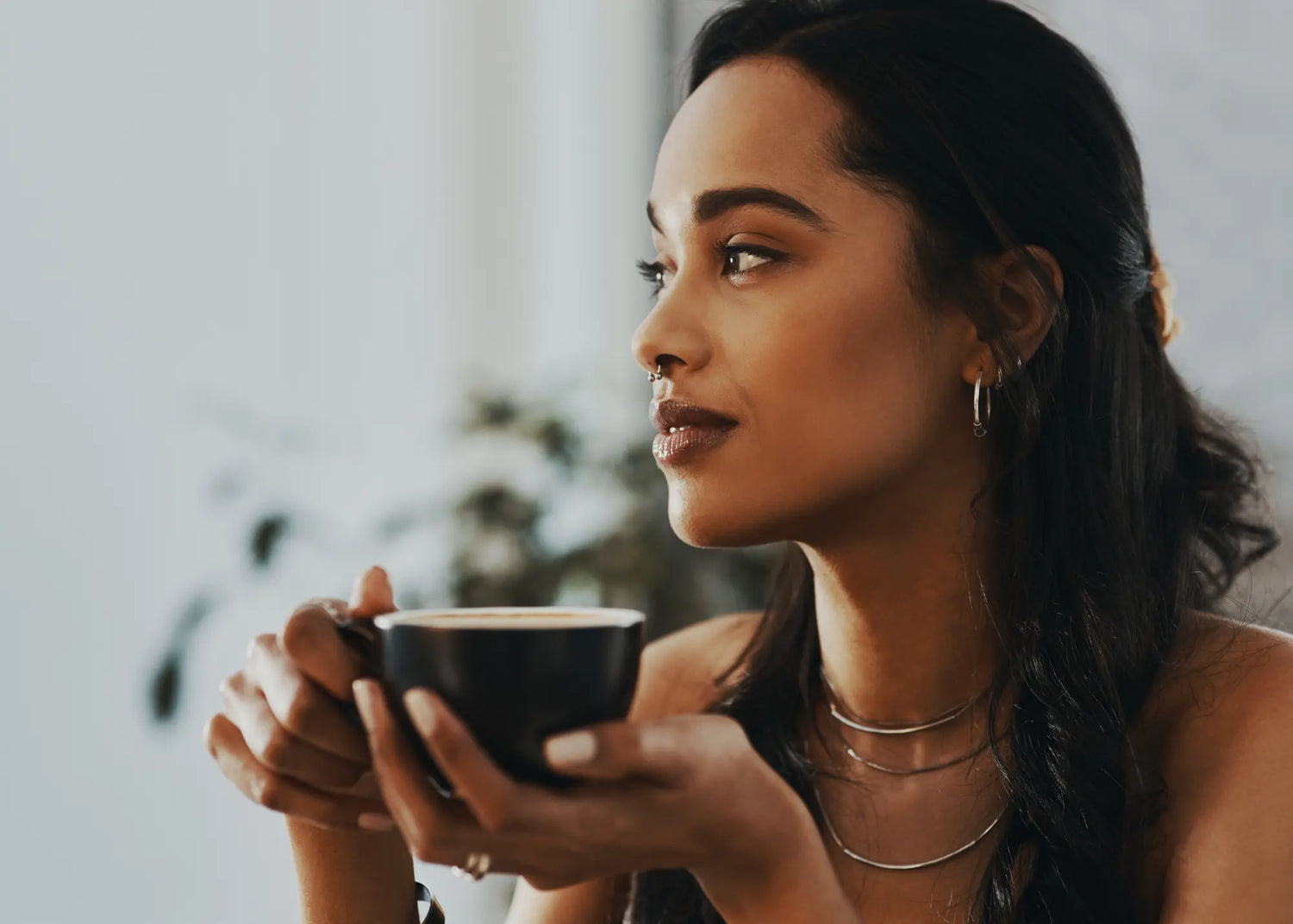 Woman holding a coffee cup with a blurred indoor background