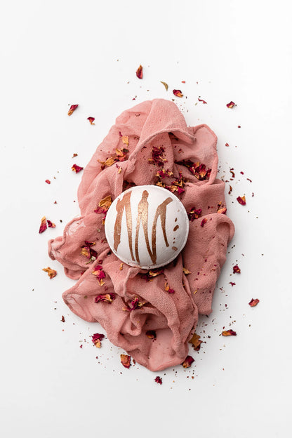 white bath bomb with a copper drizzle on a pink muslin cloth