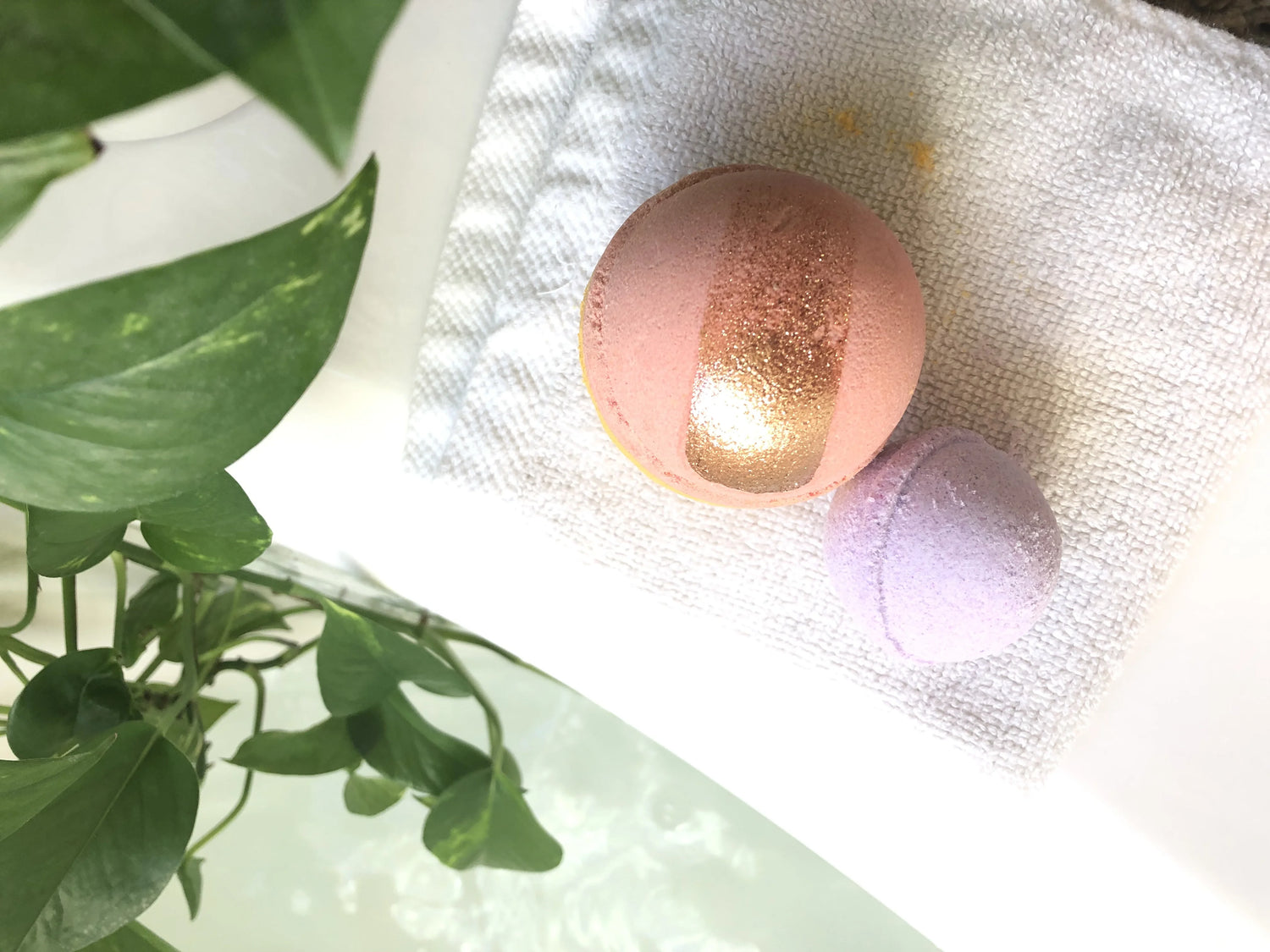 Pink and gold spherical object on a white fabric background with green leaves.