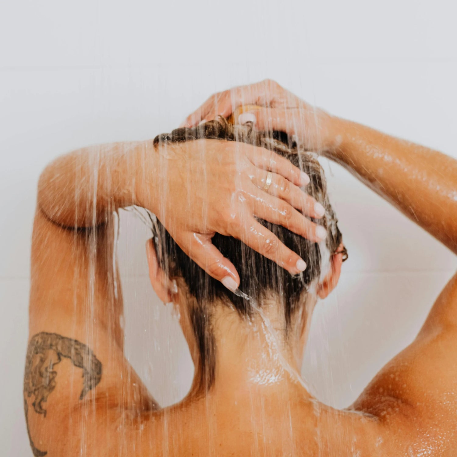 Person washing their hair with water in a bathroom setting