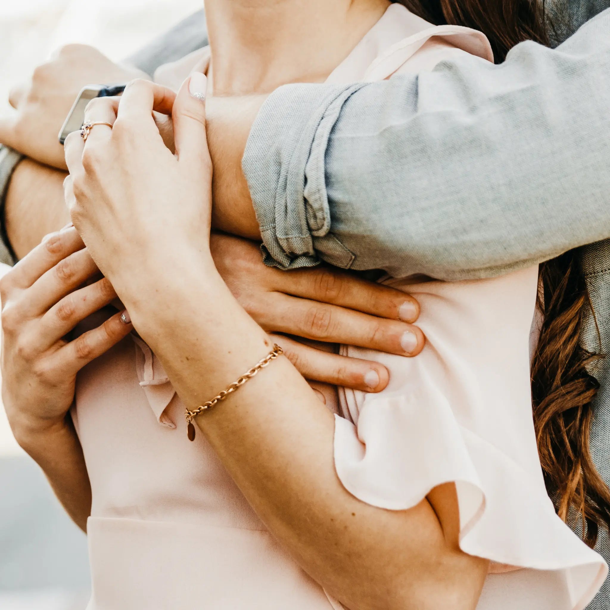 Close-up of two people embracing, with one person wearing a gold bracelet.