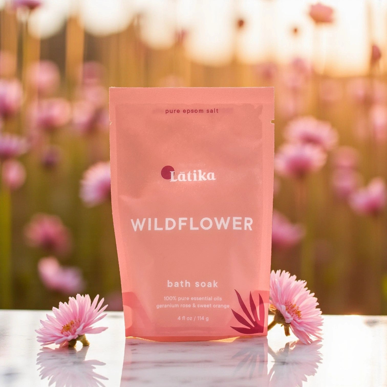 wildflower bath salt bag on a marble surface with pink flowers around and a natural flwer field background