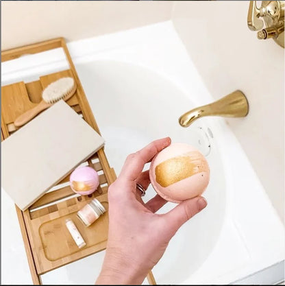Hand holding a bath bomb next to a sink with bathroom items in the background