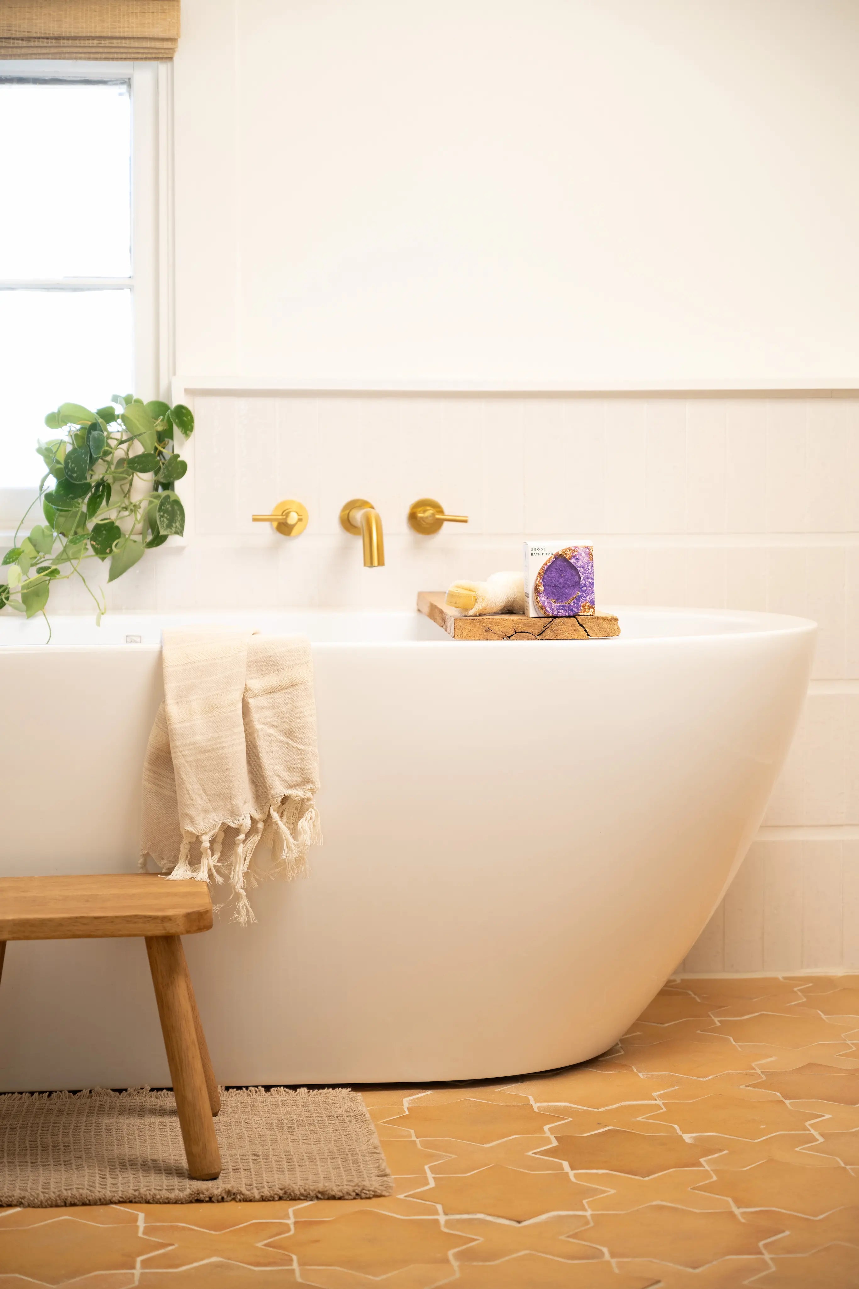 Bathroom with a freestanding bathtub, wooden stool, and decorative elements.