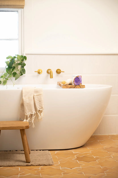Bathroom with a freestanding bathtub, wooden stool, and decorative elements.