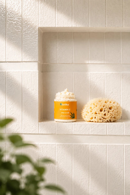 A jar of Indian Vitamin C Face Wash with white foam, displayed on a tiled shelf next to a natural sponge, with soft shadows and blurred green leaves in the foreground.