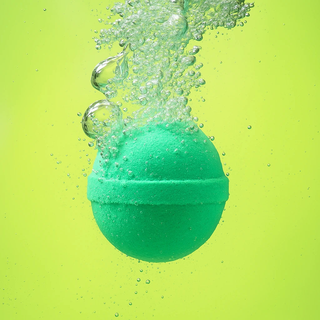 green bath bomb submerged in water with a light green background and berry vanilla scent