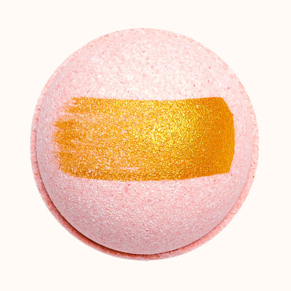 Pink bath bomb with a gold stripe on a white background