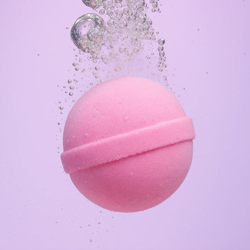 pink bath bomb submerged in water with bubbles and light purple background