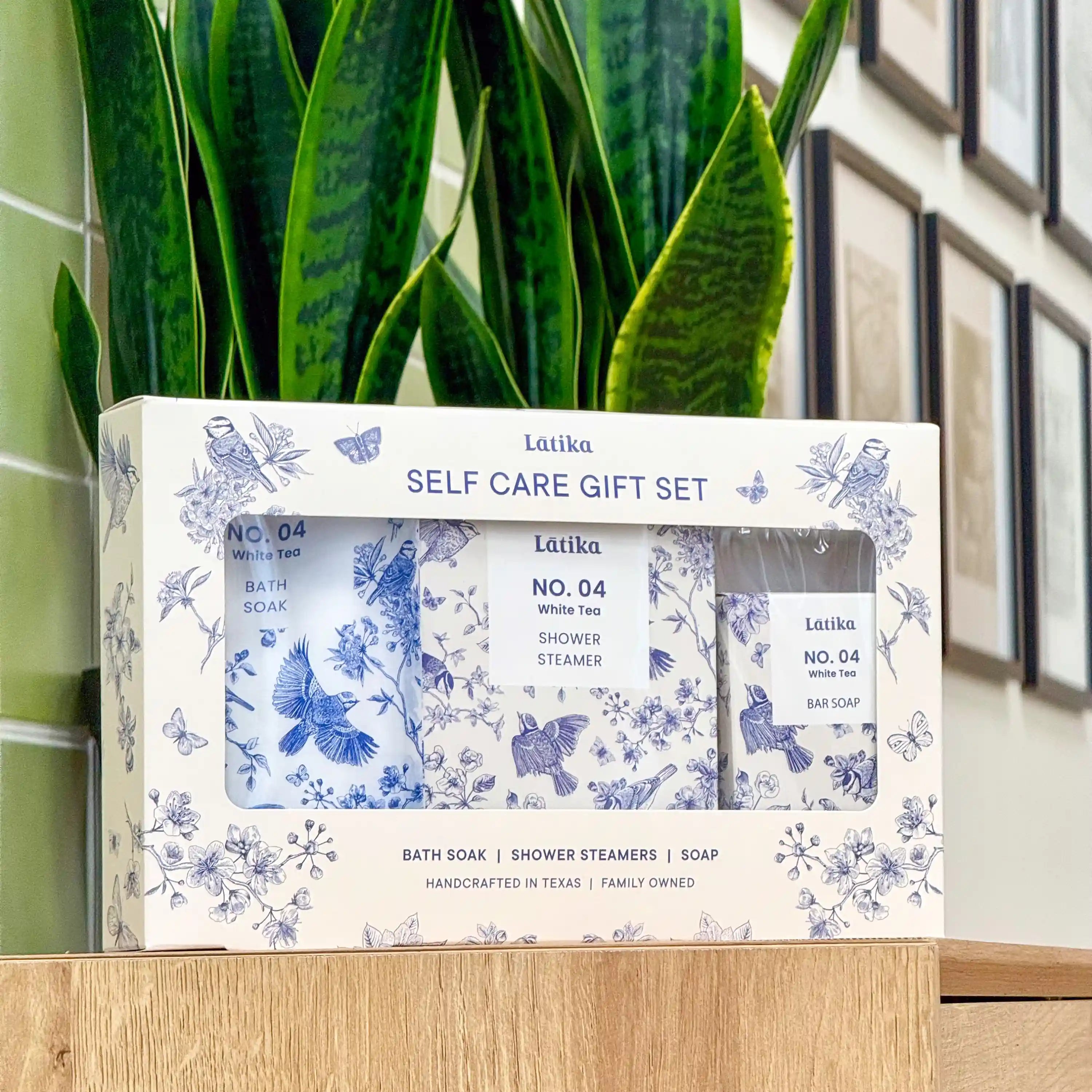 Latika self-care gift set with bath soap, shower steamer, and soap in front of a green plant. chinoiserie pattern box.