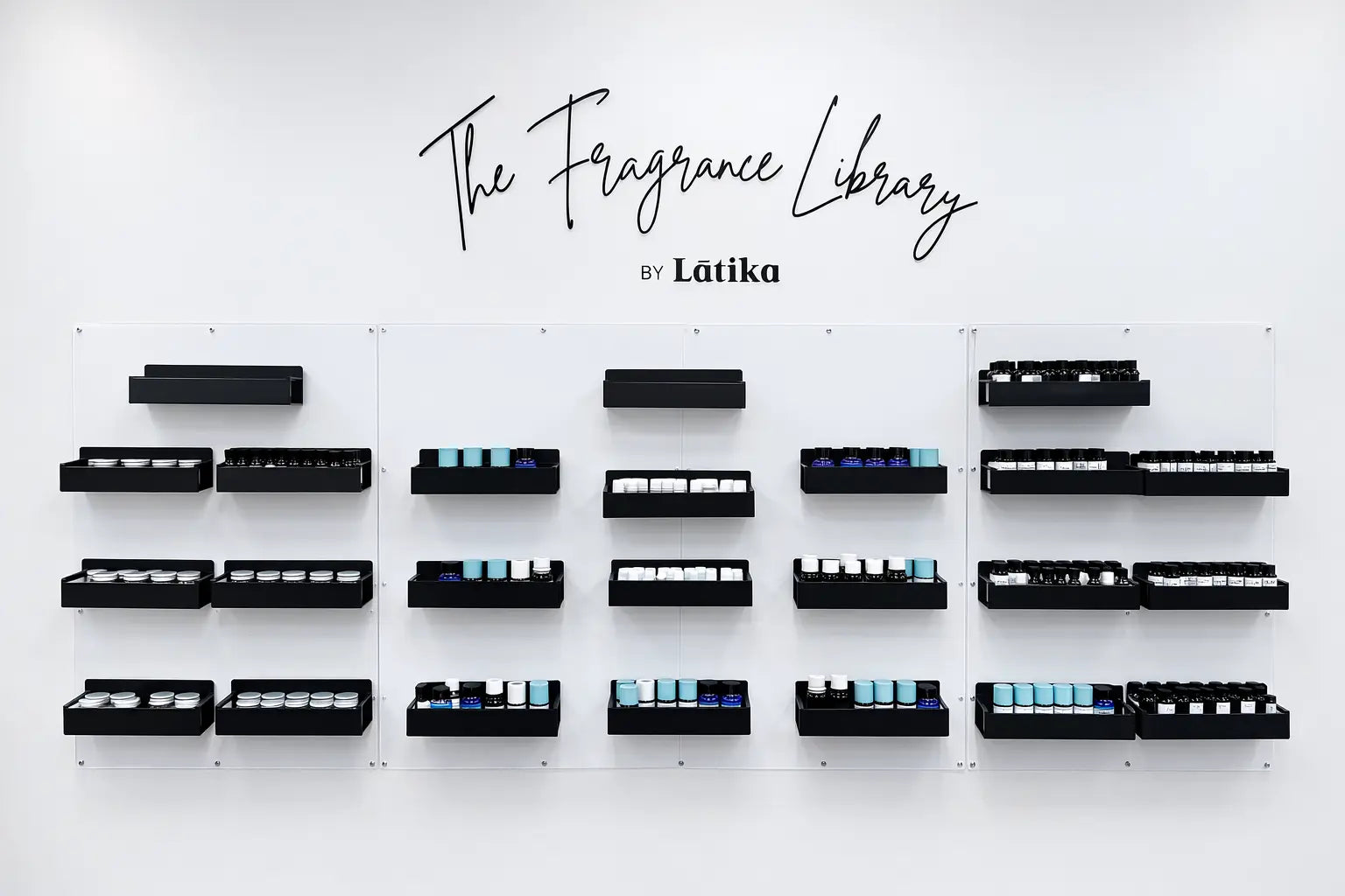 Wall display of black fragrance bottles with 'The Fragrance Library by Latika' branding.