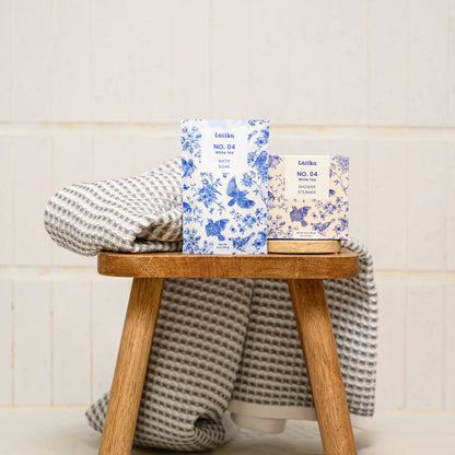 Latika milk bath soak in white tea and whiite tea shower steamers on a bath stool
