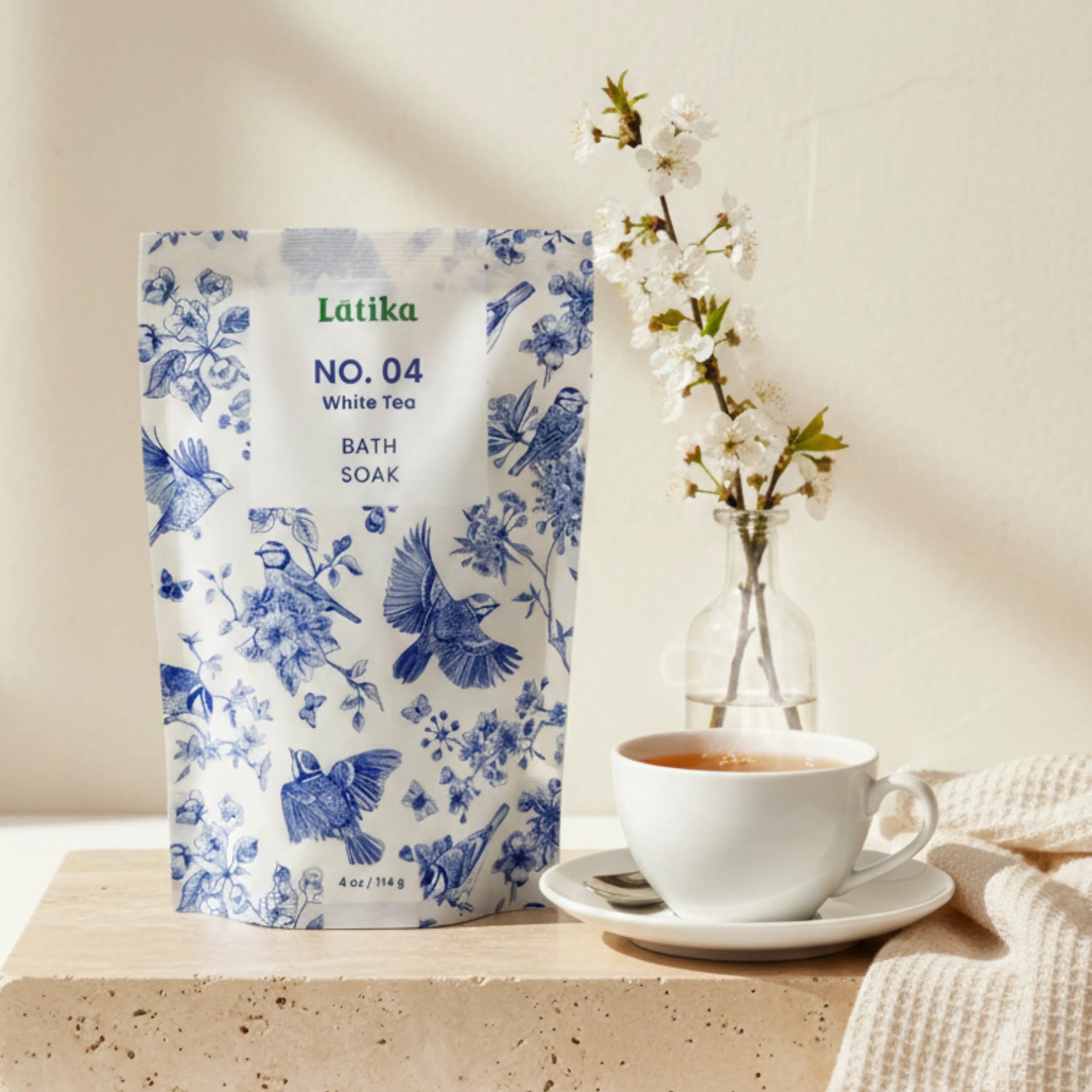 Latika No. 04 White Tea Bath Soak packaging with a cup of tea and flowers on a neutral background