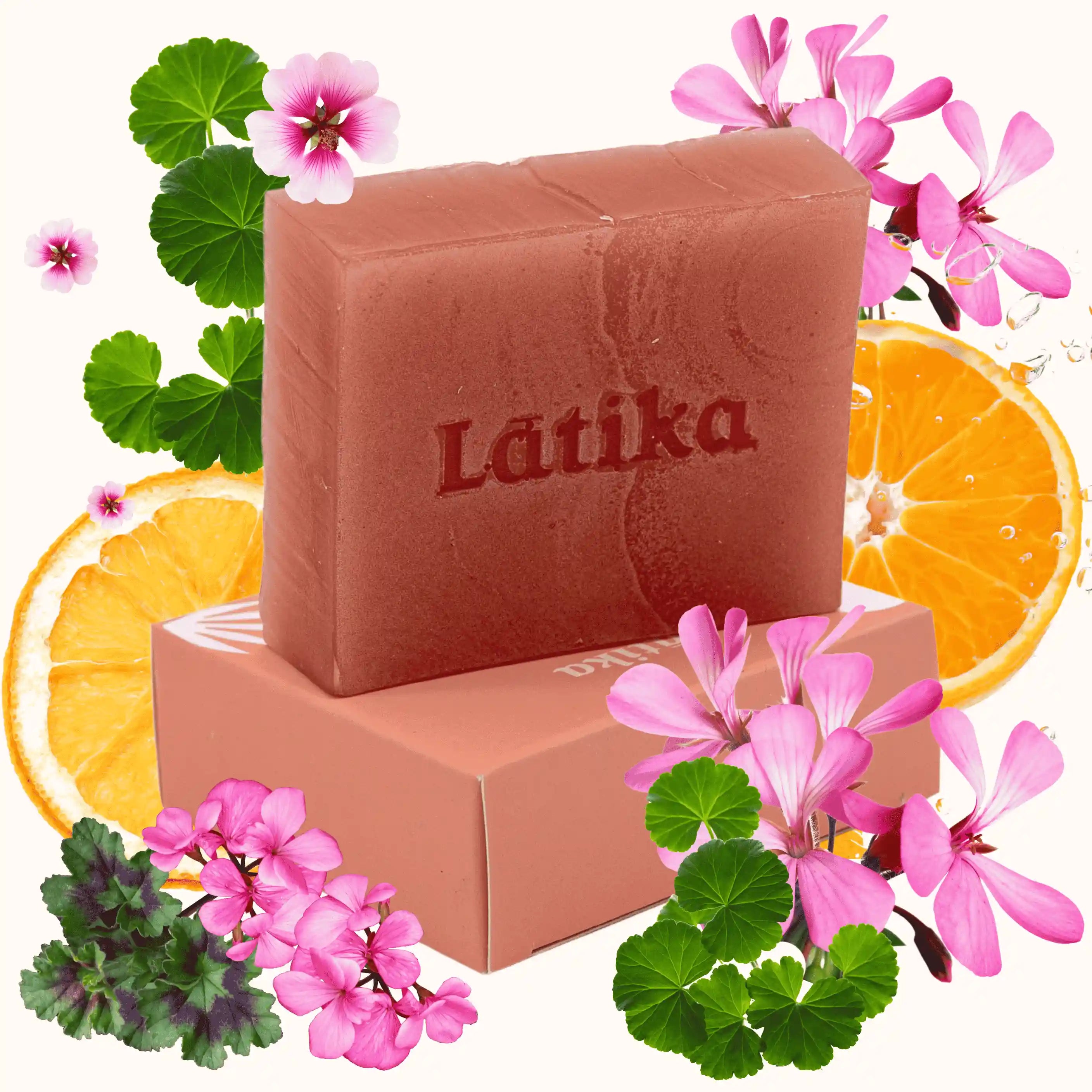 Bar of Latika soap with orange slices and flowers on a white background